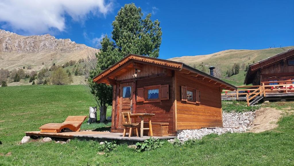 a small cabin in a field with mountains in the background at Chalet El Baitel in Bellamonte
