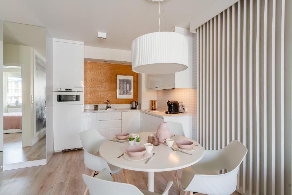 ein weißes Esszimmer mit einem weißen Tisch und Stühlen in der Unterkunft APT Nadmorskie - Bliżej Morza in Kołobrzeg