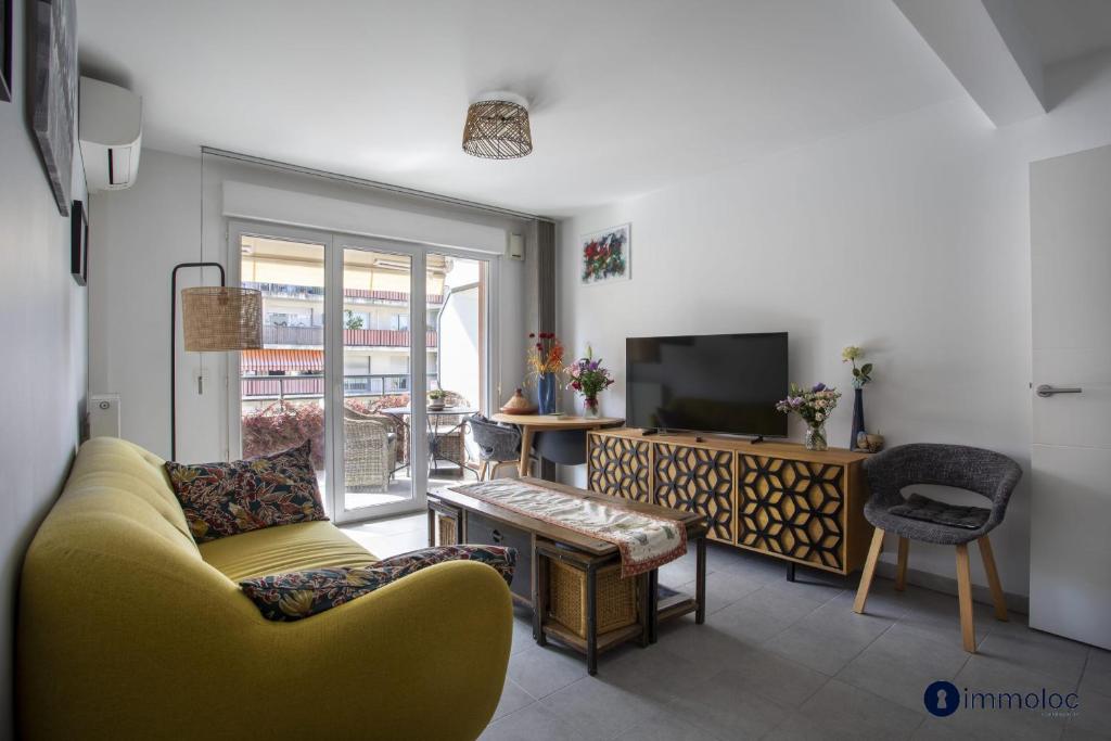 un salon avec un canapé jaune et une télévision dans l'établissement Air-conditioned apartment near Libération district, à Nice