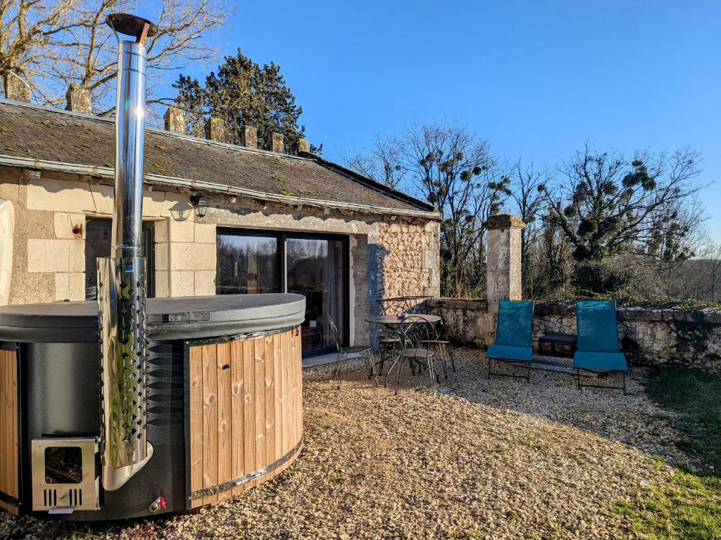 a stone house with a wood stove and two blue chairs at Séjour Historique au Domaine de Migny : Gîte avec Bain Nordique et Piscine - FR-1-591-731 in Saint-Cyran-du-Jambot