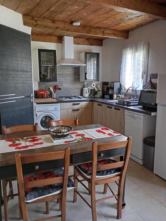 - une cuisine avec une table, des chaises et une cuisinière dans l'établissement Gîte les coquelicots, à Saint-Sèbastien