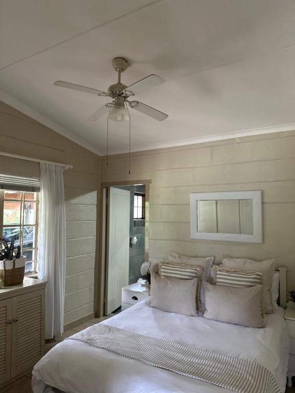 ein Schlafzimmer mit einem weißen Bett mit Deckenventilator in der Unterkunft The Coastal at Marina Glen Holiday Resort in Marina Beach