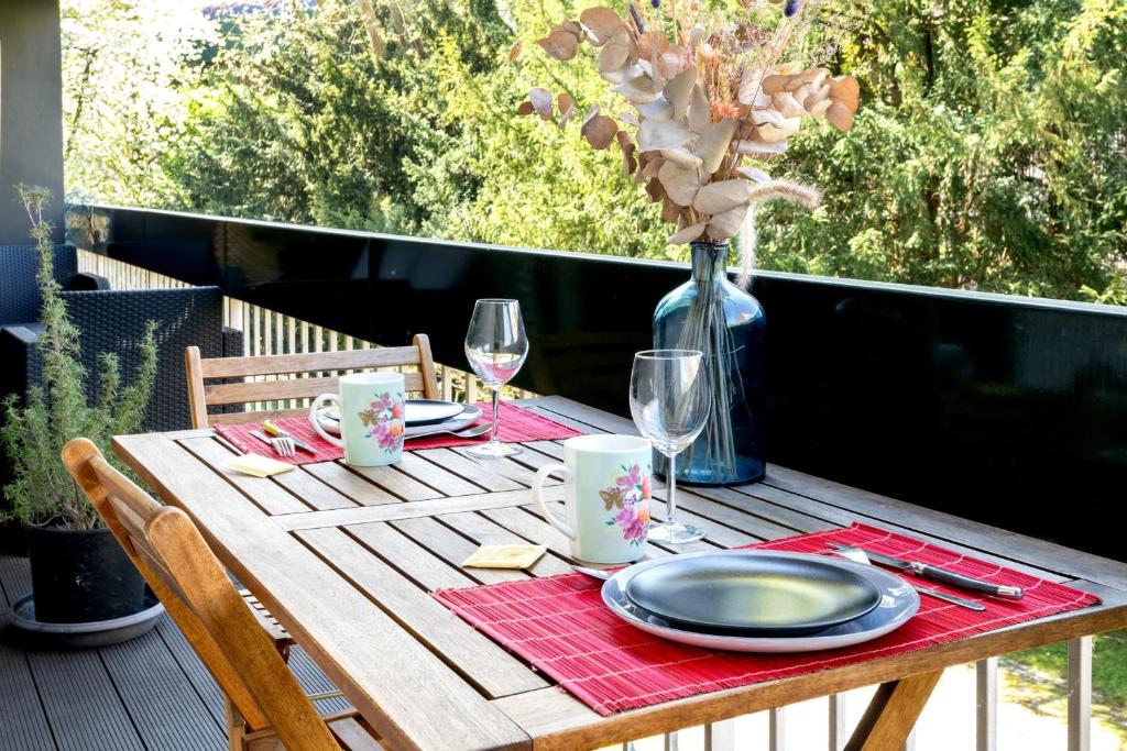 une table en bois avec des assiettes, des verres et un vase dans l'établissement Appartement Bellevue - Welkeys, à Boulogne-Billancourt
