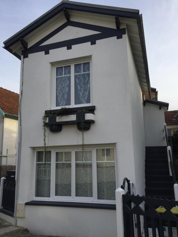 une maison blanche avec une grande fenêtre et des escaliers. dans l'établissement Petit bijoux, à La Tremblade