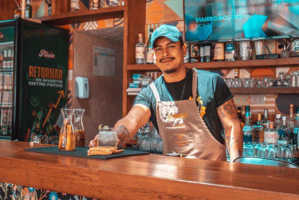 a man standing behind a bar with a drink at Viajero Cusco Hostel in Cusco