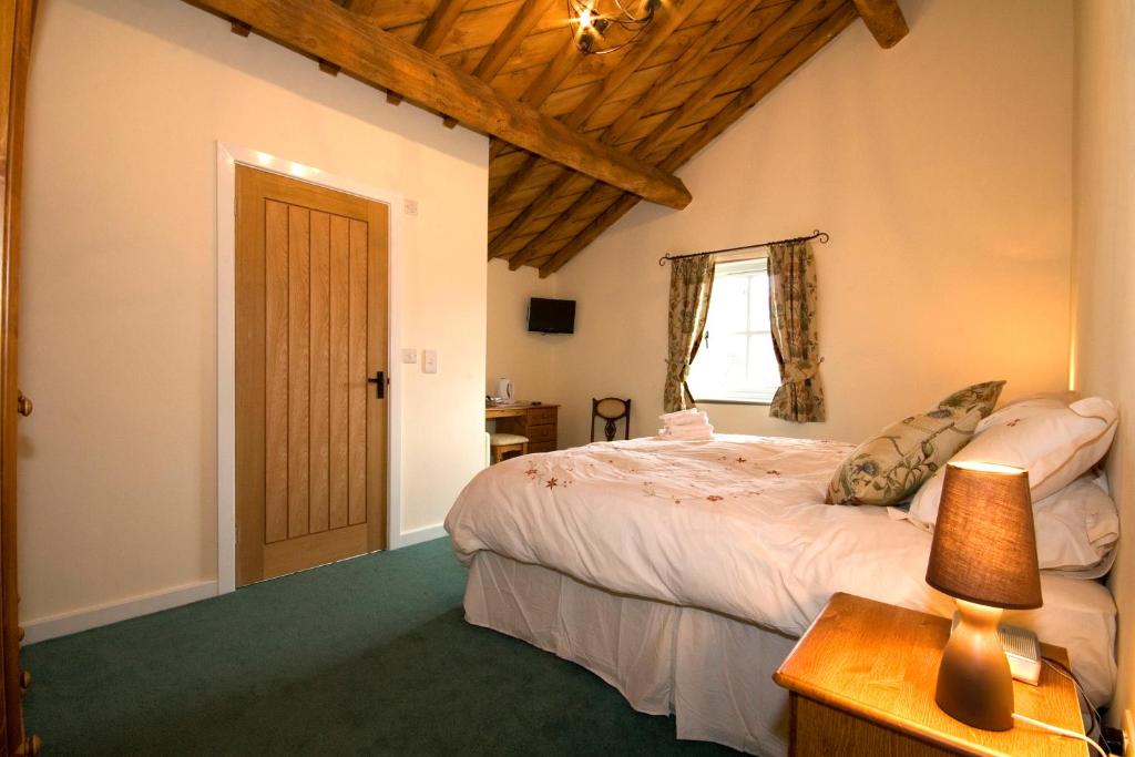 a bedroom with a bed and a table with a lamp at The Farm Burscough in Burscough