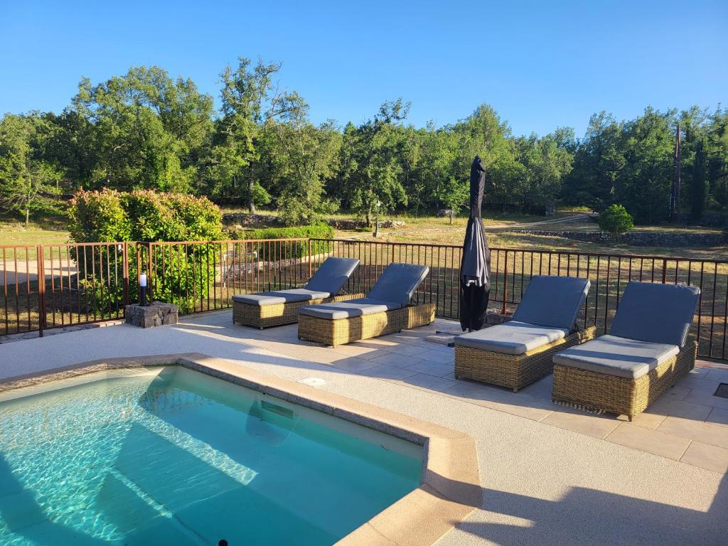 une piscine avec des chaises longues et un parasol dans l'établissement Maison au calme absolue, à Saint-Cézaire-sur-Siagne