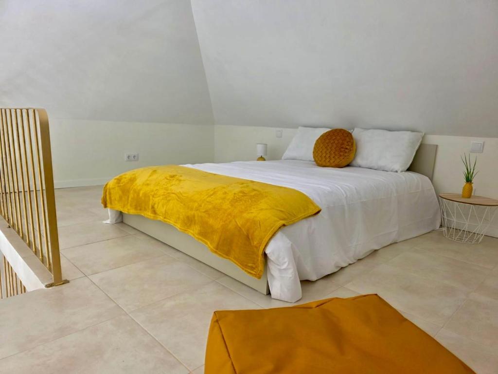 a bedroom with a bed with a yellow blanket on it at Casa da Vila in Machico