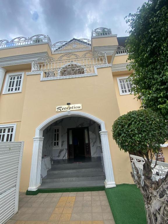 a large yellow building with a door and stairs at Presken Hotel OPEBI Branch in Lagos