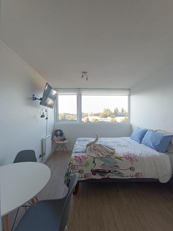 une chambre avec un lit, une table et une fenêtre dans l'établissement Kasa & Familia, à Valdivia