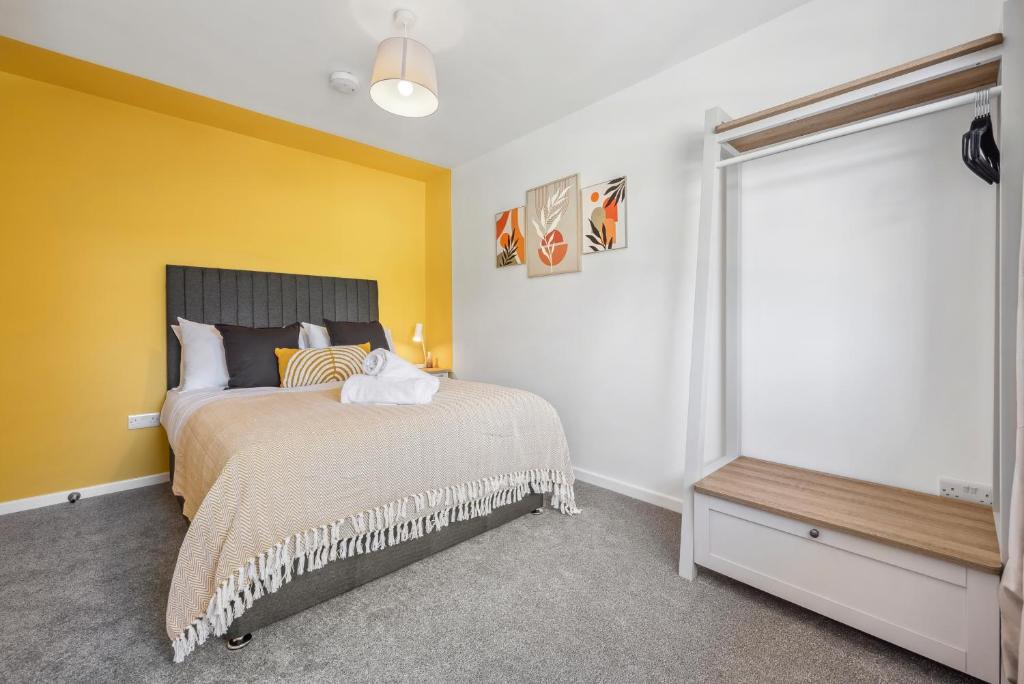 a bedroom with a bed and a yellow wall at Cotswolds Vista, 3 bed, 2 bathrooms, complimentary parking in Cirencester