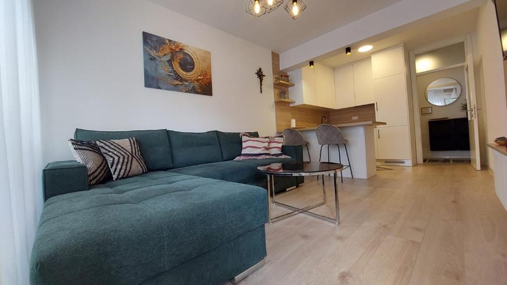 a living room with a green couch and a kitchen at Apartman Petra in Čapljina