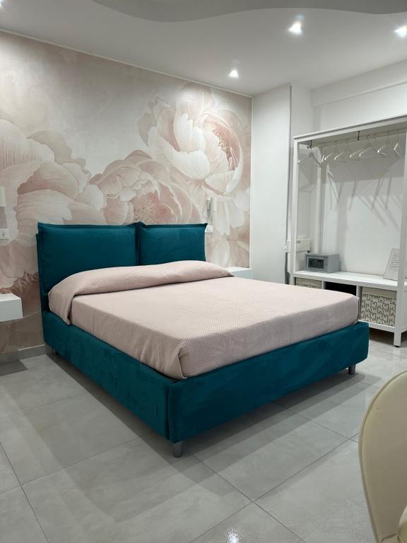 una camera con letto blu e murale floreale di B&B Chiedi la Luna a San Vito lo Capo