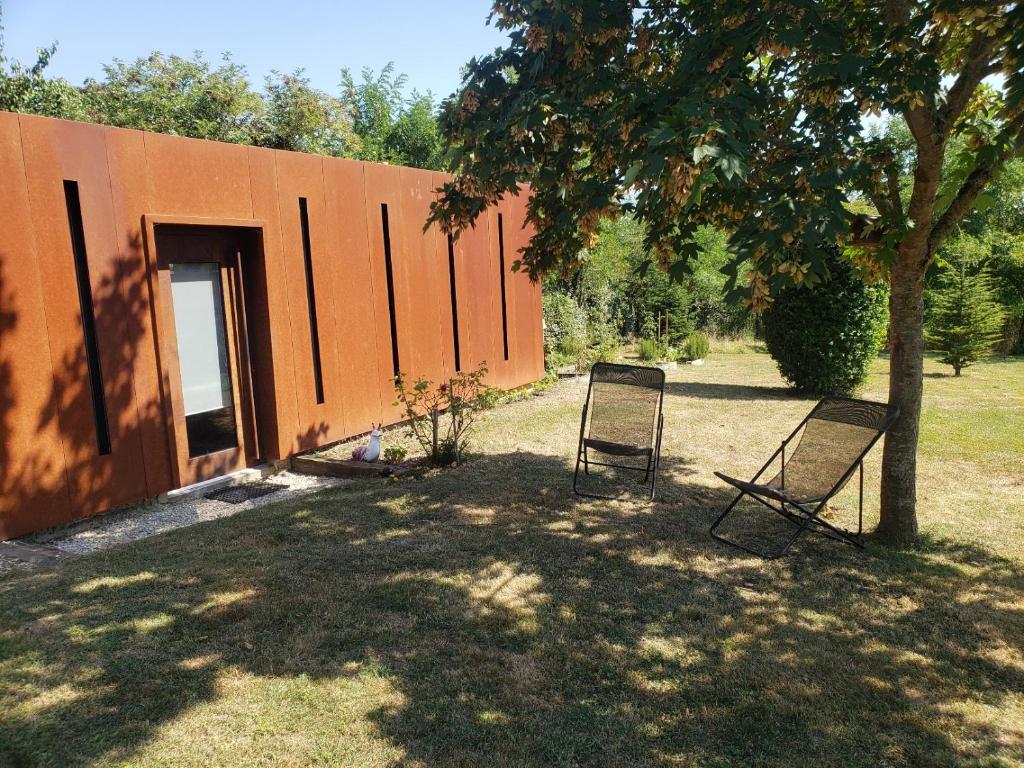 two chairs sitting under a tree next to a building at Calme et Confort sur les Hauteurs de Montauban in Montauban
