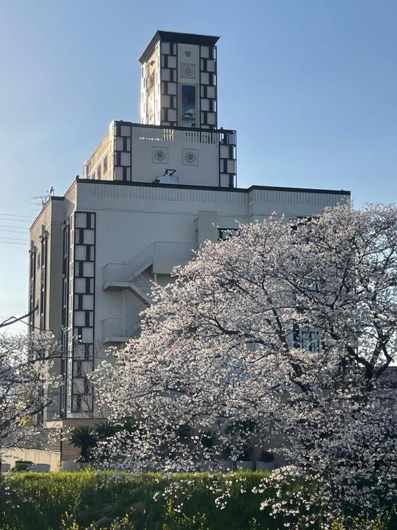 un bâtiment doté d'une tour d'horloge avec des akuraakura devant lui dans l'établissement AURA Resort Nara (Adult Only), à Nara
