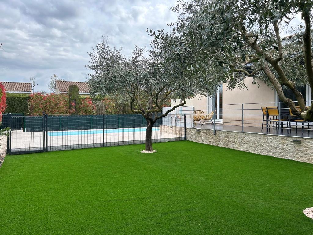 une cour verdoyante avec un arbre et une clôture dans l'établissement Villa Cigalette avec piscine, terrasse et jardin, à Moussac