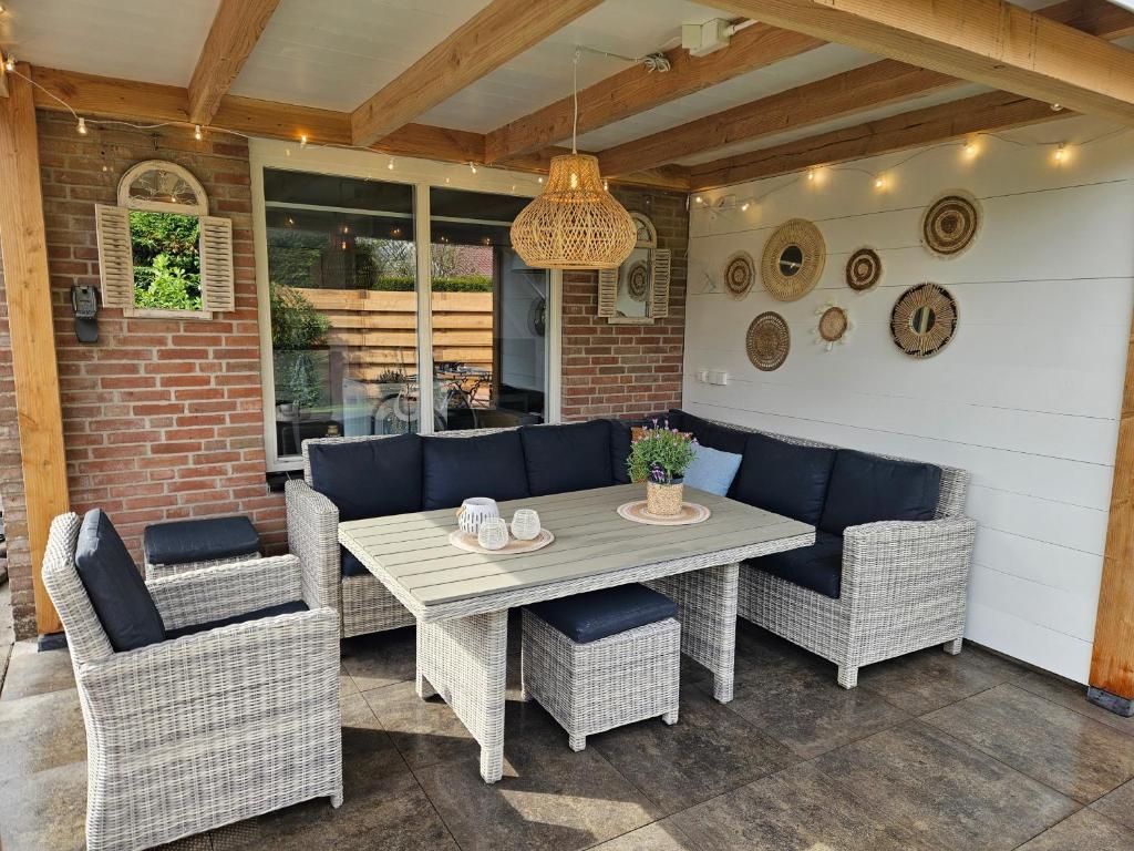 a patio with a table and wicker chairs at Bungalow Schotvanger in Egmond aan den Hoef