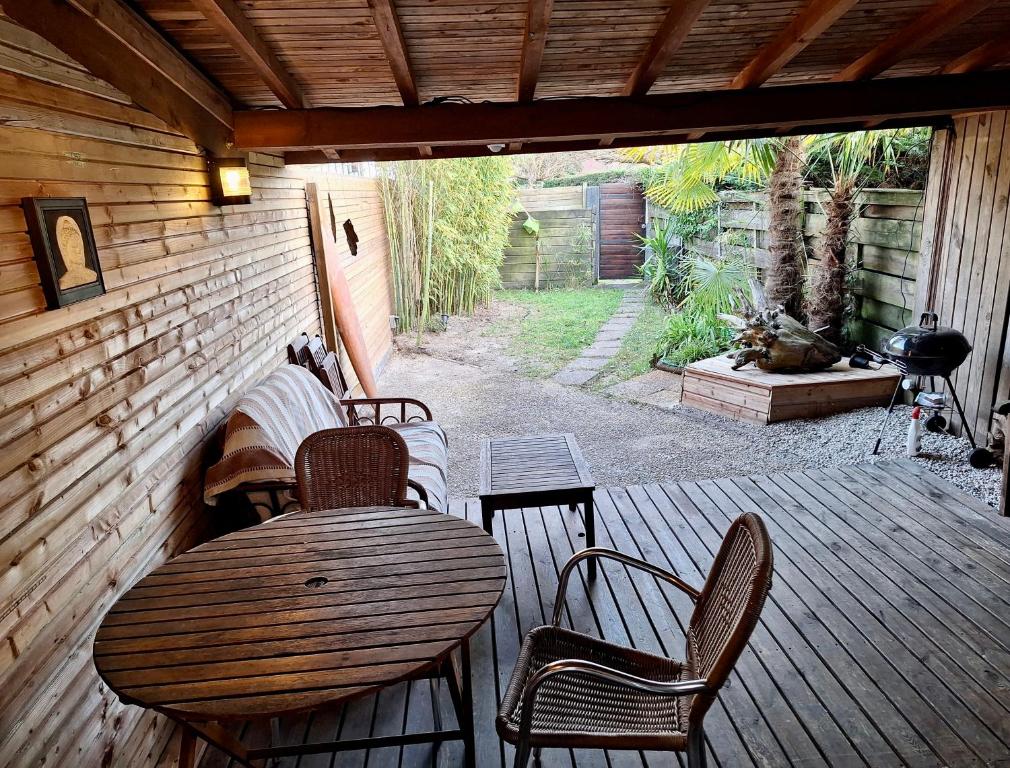 d'une terrasse en bois avec une table et des chaises. dans l'établissement Aux portes de l'océan, à Labenne