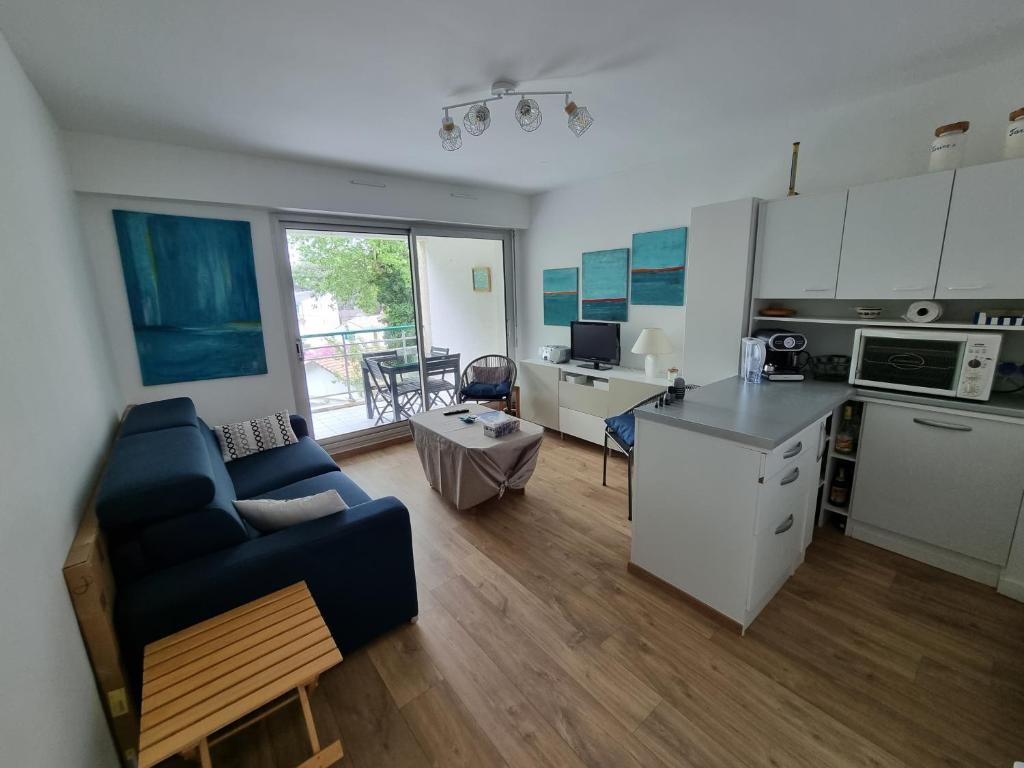 un salon avec un canapé bleu et une cuisine dans l'établissement Les Dryades 4 pax appartement, à La Baule