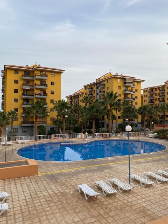 a swimming pool with lounge chairs and buildings at BRISAS DEL MAR Eddy,,AIR,WIFI in Candelaria