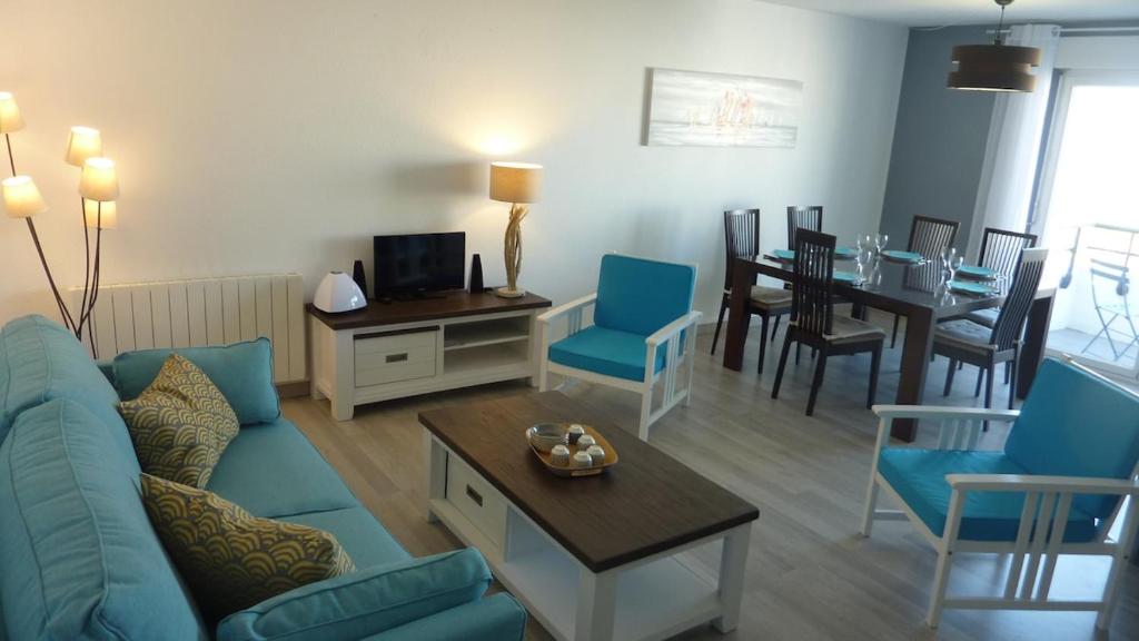 un salon avec un canapé bleu et une table dans l'établissement T3 lumineux tout confort aux portes de la Rochelle, à Aytré