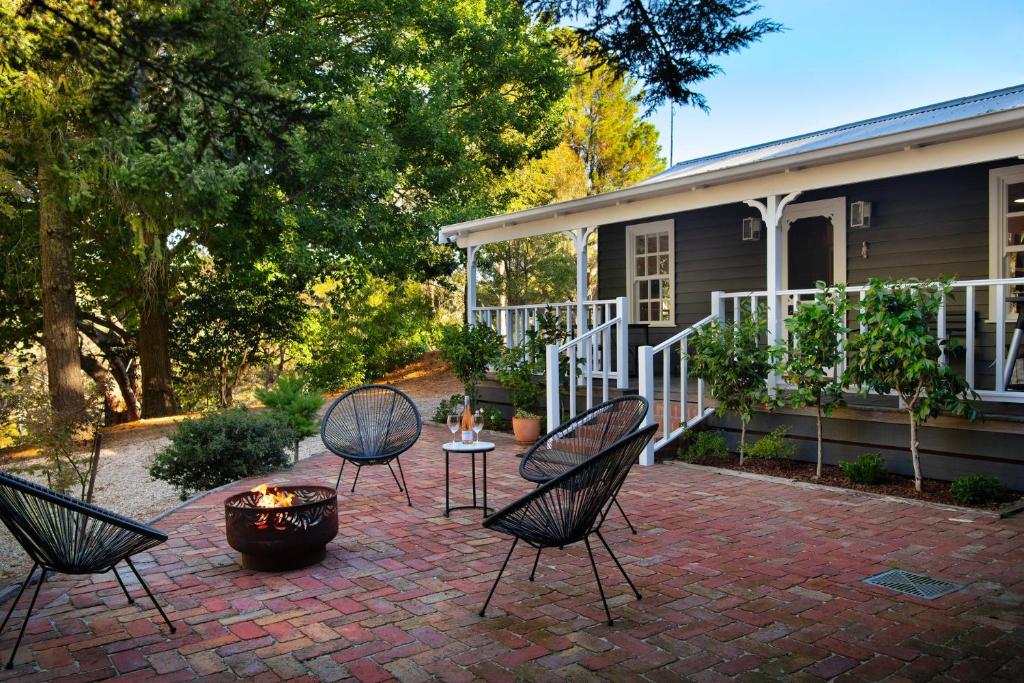 a patio with four chairs and a fire pit in front of a house at Wrenwood Cottage- outdoor spa in serene setting in Daylesford