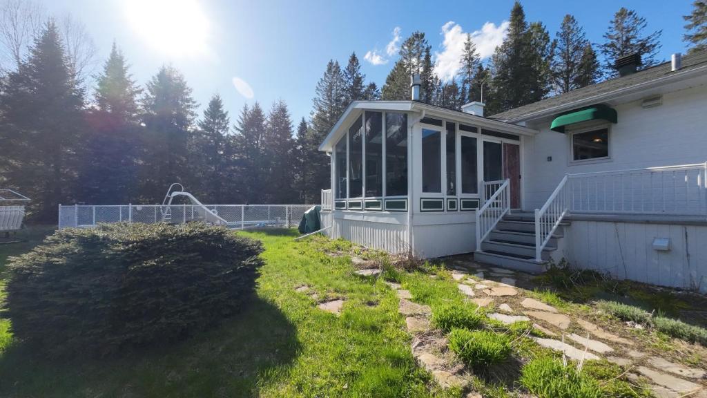 a white house with a porch and a yard at Cottage with inground pool outside in Saint-Damien