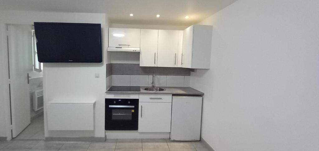 une petite cuisine avec des armoires blanches et un évier dans l'établissement Studio centre ville de Gagny, à Gagny