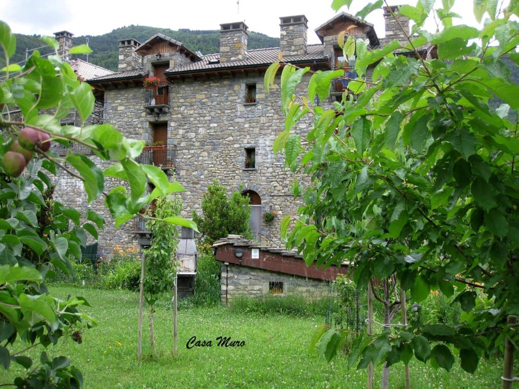 un antiguo edificio de piedra con árboles delante de él en Casa Muro Ordesa en Frajén