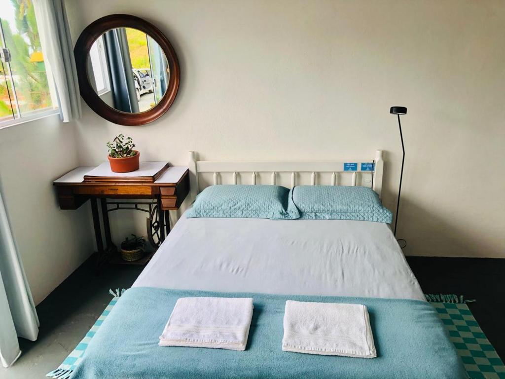 a bedroom with a bed with two towels on it at Pousada LUGAR - Quarto MAR familiar e tranquilo in Penha