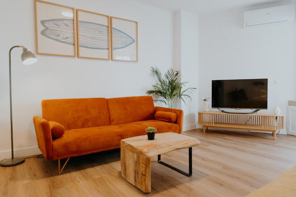 ein Wohnzimmer mit einem orangenen Sofa und einem TV in der Unterkunft Apartamento Hermi in Torrox