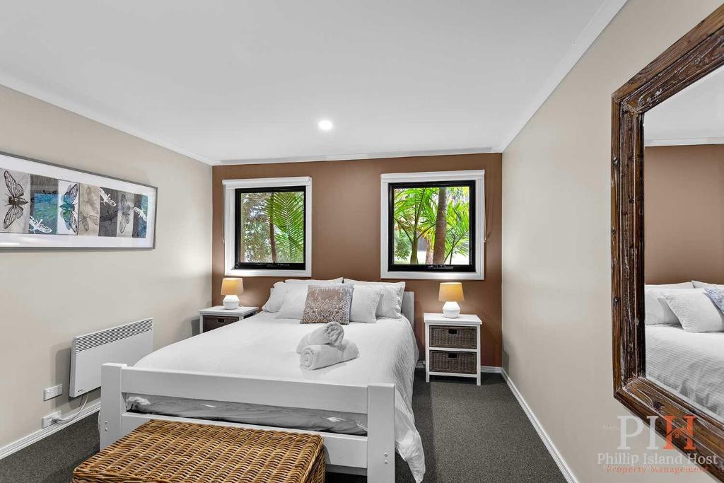 Un dormitorio con una cama blanca y un espejo. en Cape Woolamai Beach House 10, en Cape Woolamai