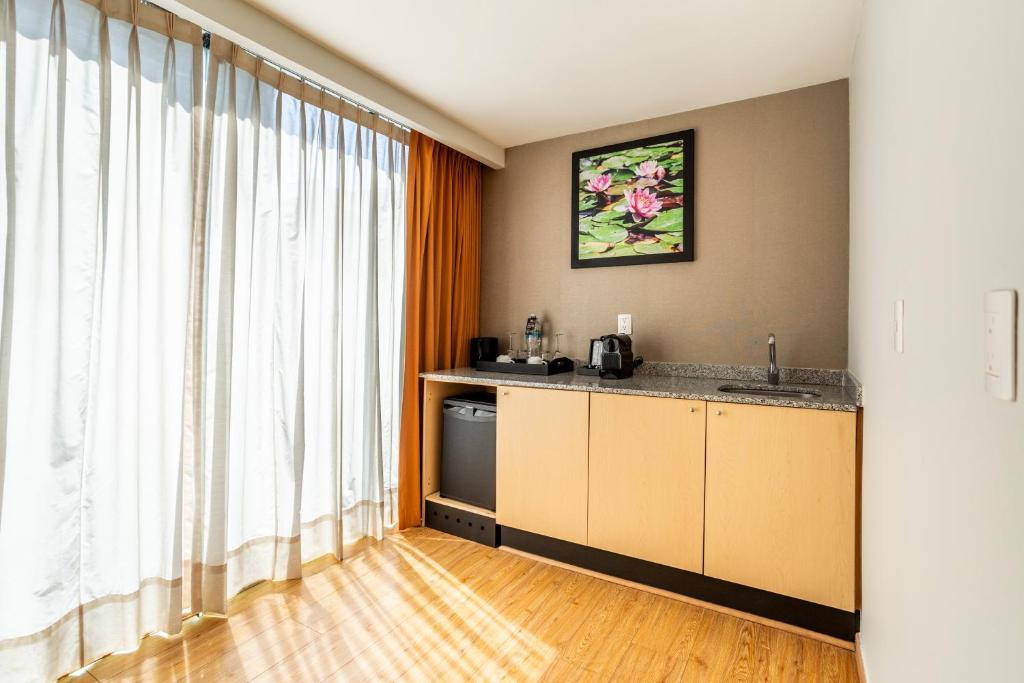 A compact kitchenette with a sink, under-counter refrigerator, kettle, and coffee setup.