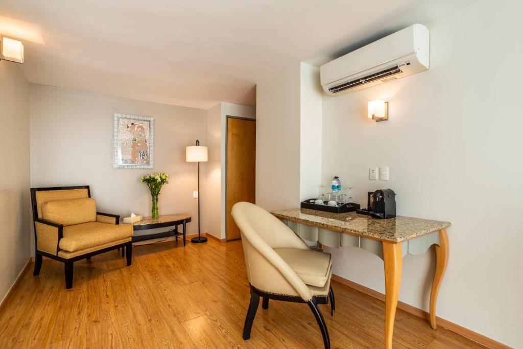 A compact in-room workspace beside a lounge chair and air conditioner.
