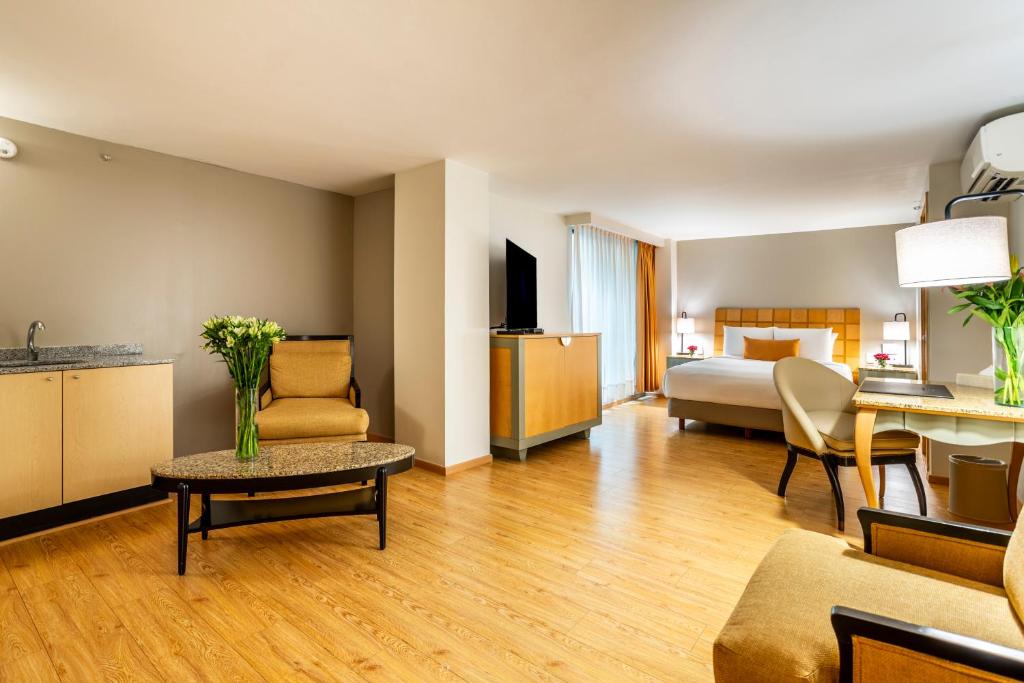 A spacious room combines a bedroom, lounge seating and a compact kitchenette.