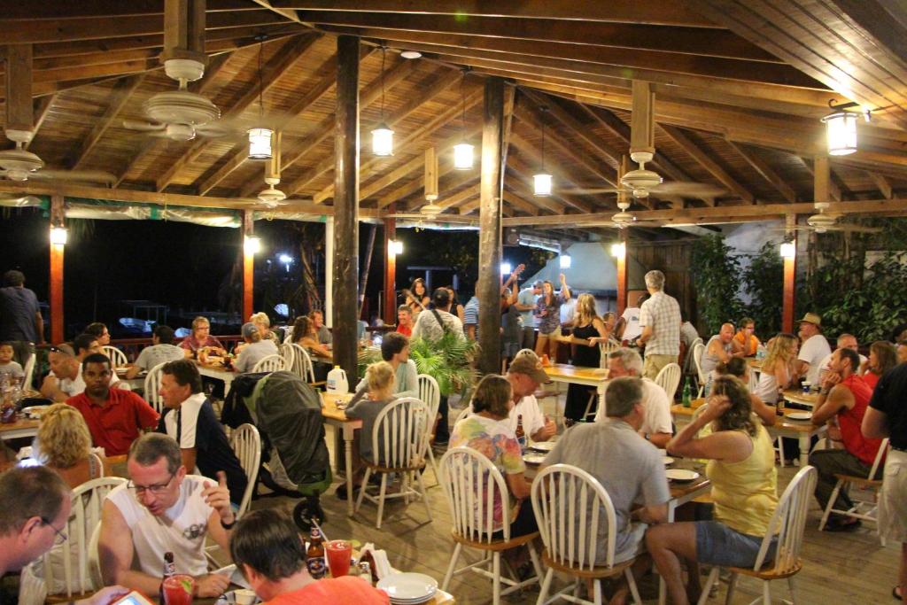a group of people sitting at tables in a restaurant at Splash Inn Dive Resort & Villas in West End