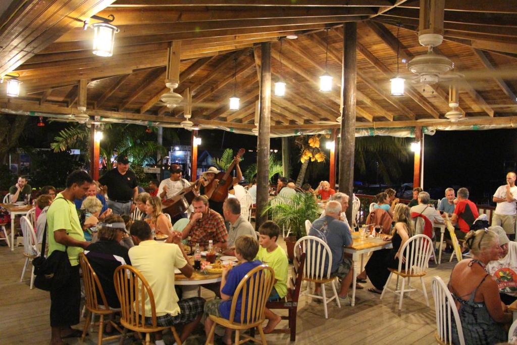 a group of people sitting at tables in a restaurant at Splash Inn Dive Resort & Villas in West End
