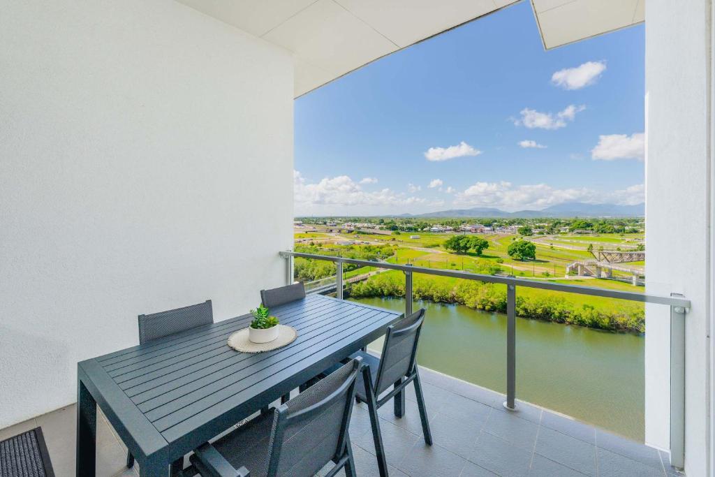 - Balcón con mesa y sillas y vistas al río en Home To Holiday at Holborn Apartments, en Townsville