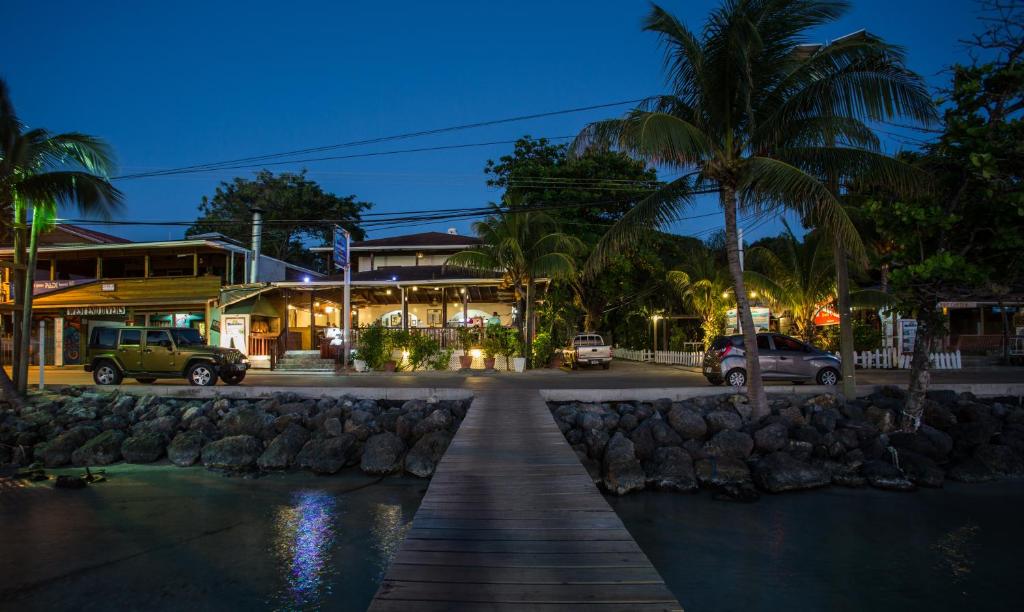 a wooden walkway in front of a building with palm trees at Splash Inn Dive Resort & Villas in West End