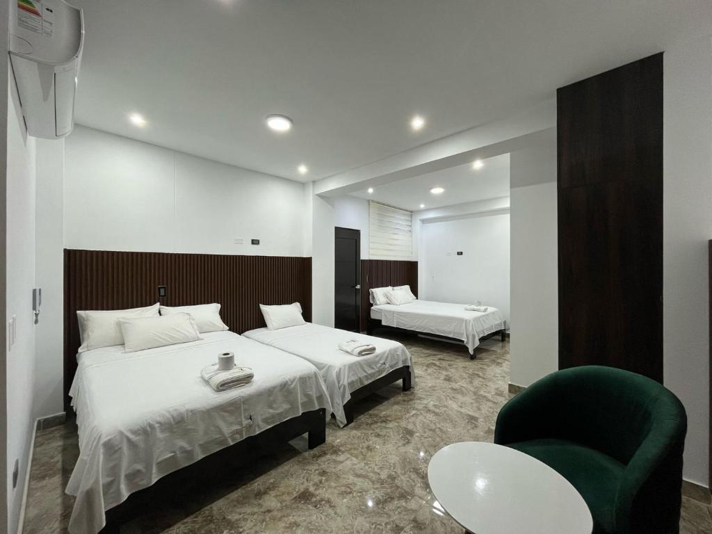 a bedroom with two beds and a green chair at Hotel San Francisco in Tarapoto