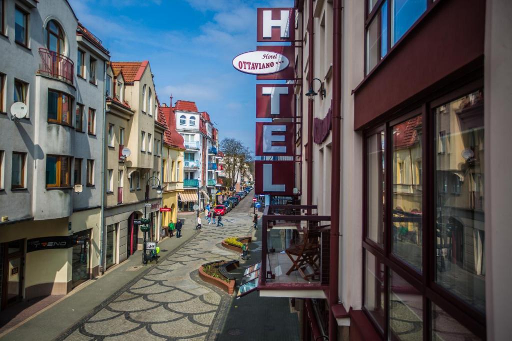 Elevated view of pedestrian street lined with pastel buildings, prominent vertical HOTEL sign.