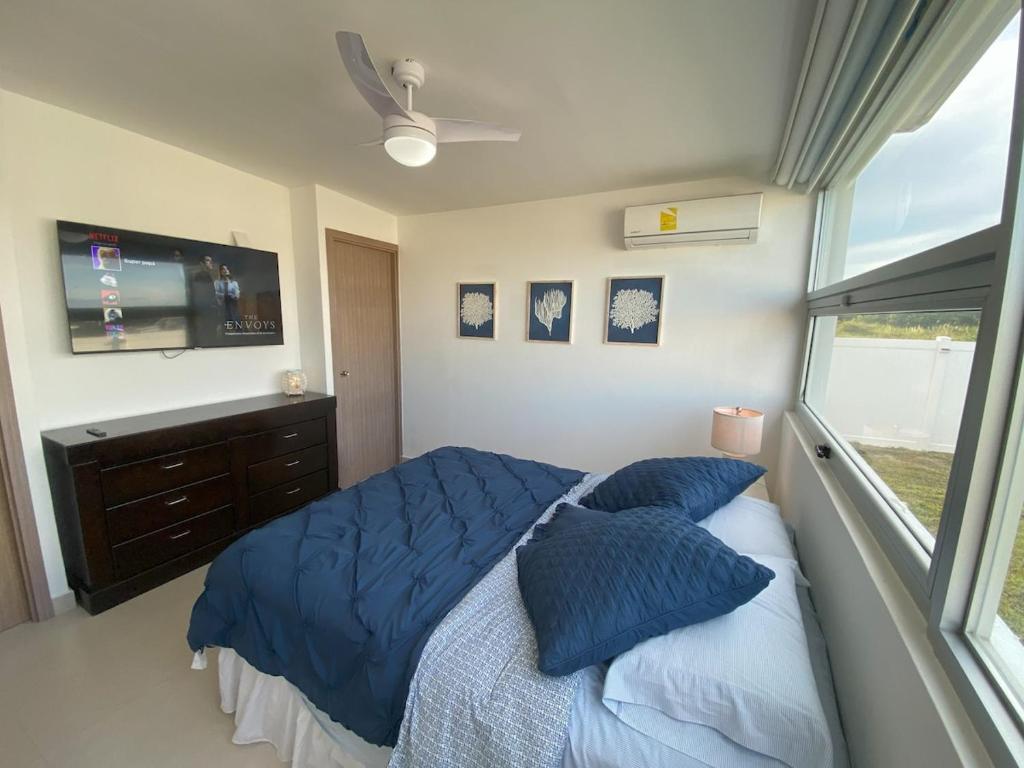 una camera da letto con un letto con cuscini blu e una TV di Summer House a Chame