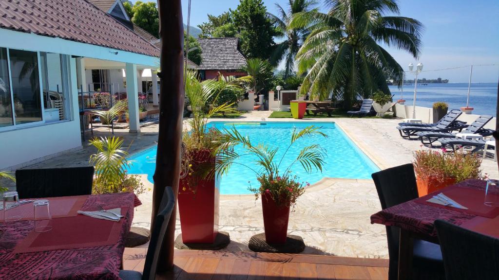 a swimming pool with palm trees and a table and chairs at Pension de famille HITI MOANA VILLA in Papara