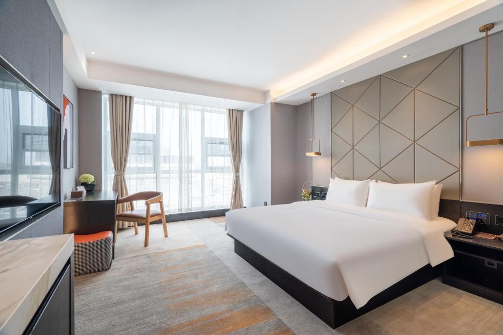 a hotel room with a large bed and a desk at 沃德酒店滕州市政府火车站店 in Tengzhou