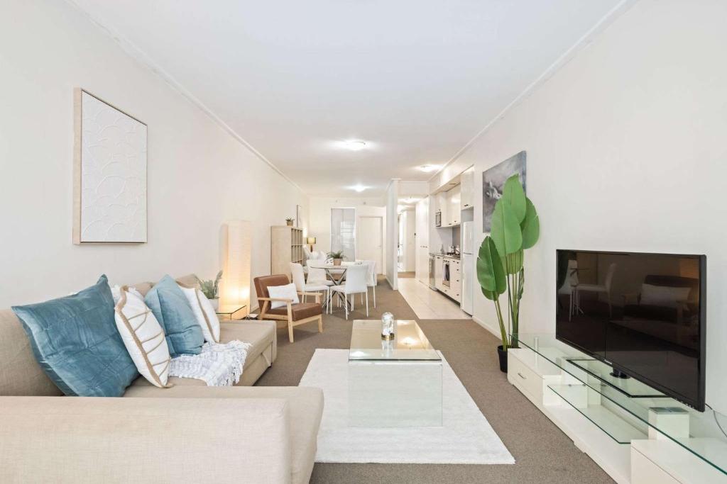 a living room with a couch and a tv at A Comfortable Studio Near Darling Harbour in Sydney