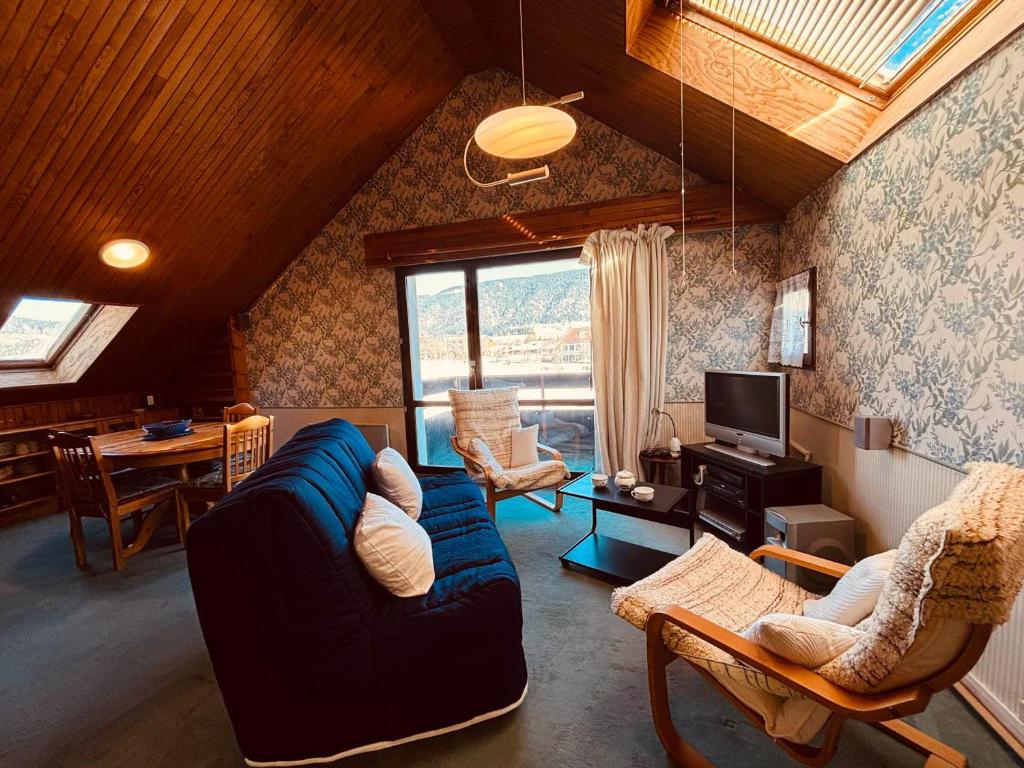 a living room with a blue couch and a tv at Appartement pour 6 pers. à Autrans, proche ski - FR-1-737-95 in Autrans