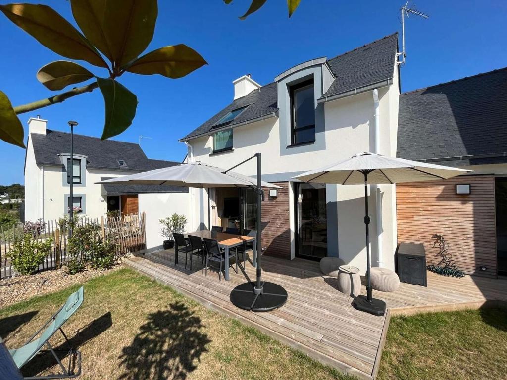 une maison dotée d'une terrasse en bois avec des parasols dans l'établissement Maison 4* à Beg Meil, proche plage avec jardin, 3 chambres, parking - FR-1-481-177, à Fouesnant