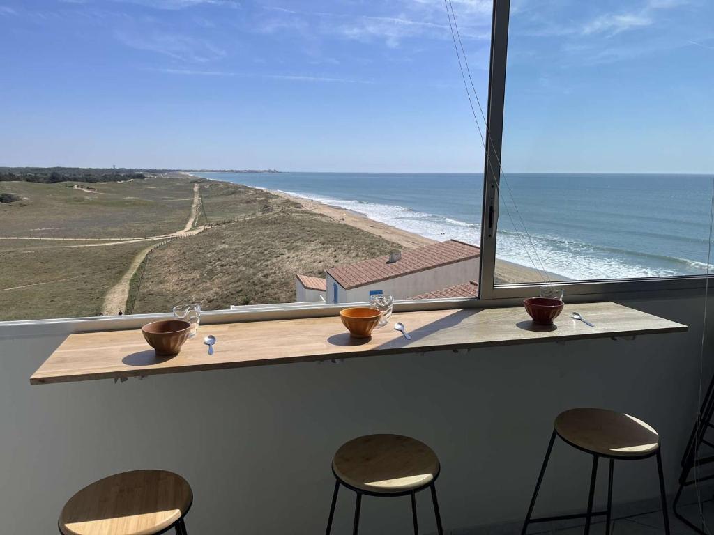 - un bar avec trois chaises et une vue sur l'océan dans l'établissement Appartement Moderne Vue Mer, Dernier Étage, Parking Privé - FR-1-324A-71, à Saint-Hilaire-de-Riez