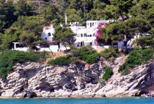 uma casa no topo de uma colina rochosa junto à água em Agistri Club Hotel em Skliri