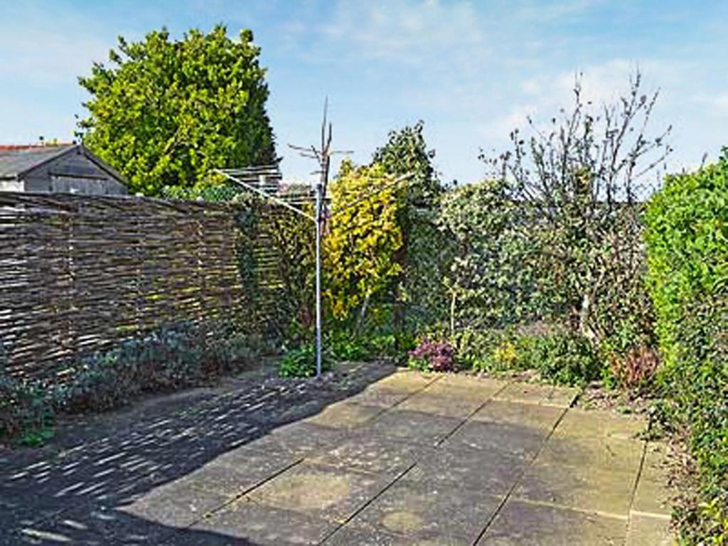 a garden with a brick wall and a fence at Wherry Cottage in Wells next the Sea